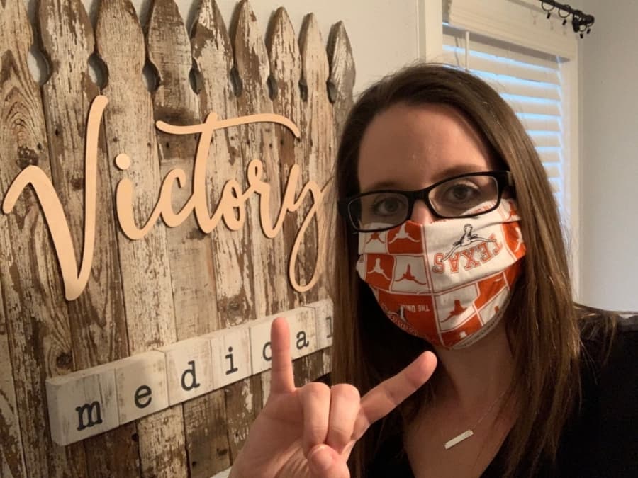 A photo of a medical workers wearing hand-sewn masks patterned with University of Texas emblems