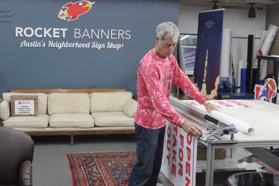 "Jimbo" prepares another roll of the banners. (Christopher Neely/Community Impact Newspaper)