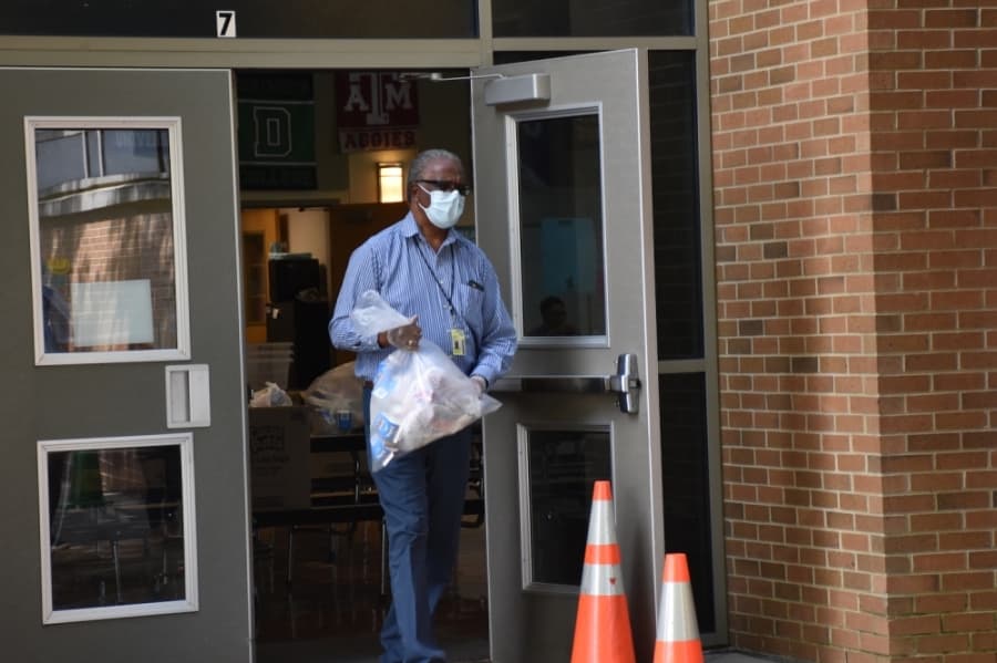 A staff member at the school prepares to hand off a meal to a parent. (Makenzie Plusnick/Community Impact Newspaper)