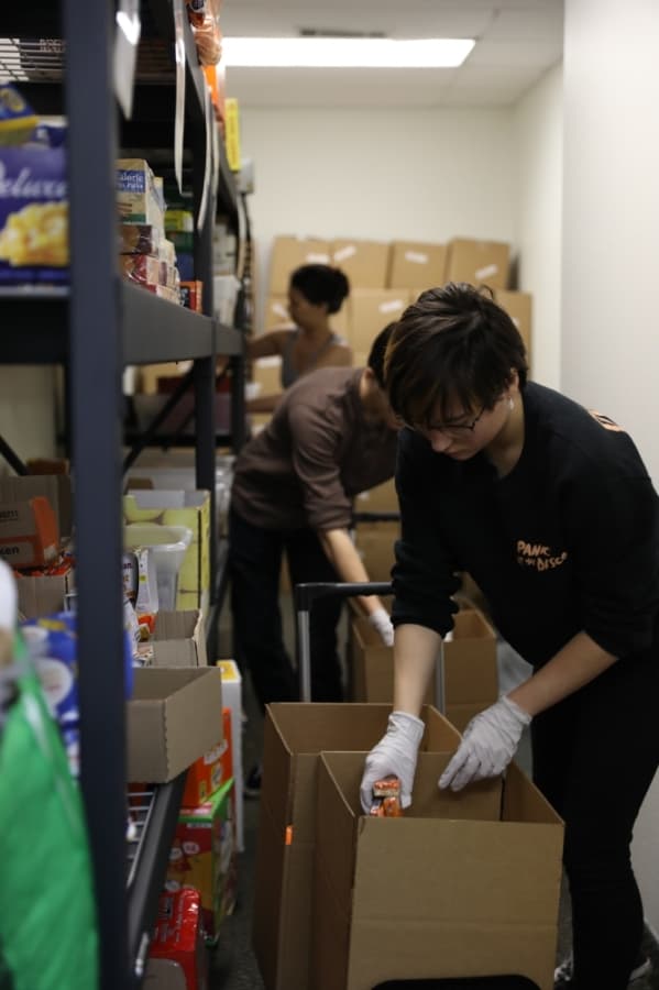 Volunteer Joelle Tindal packs Lovepacs boxes along with her brother, Preston, and mother, Sandi, who are working behind her. (Liesbeth Powers/Community Impact Newspaper)