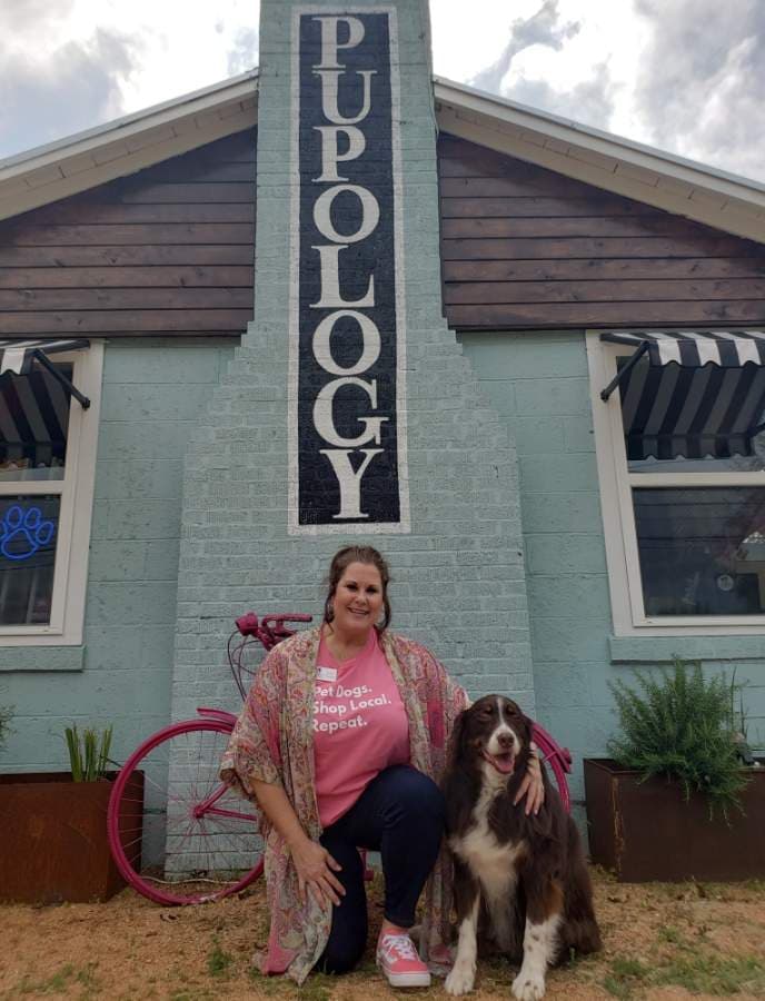 Owner Janet Cesarini with Hank, one of her five dogs, in front of her business. (Ali Linan/Community Impact Newspaper)