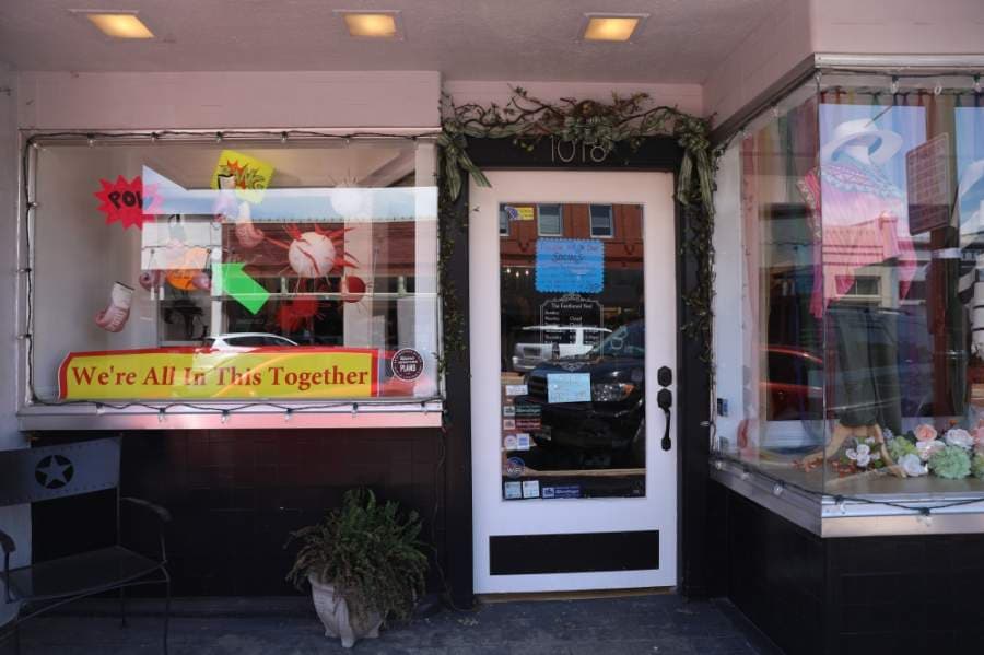 A sign in the window of The Feathered Nest in downtown Plano says, "We're all in this together." The Feathered Nest recently posted on its Facebook page, clarifying that the store is closed to any walk-in customers, but orders made in advance can be picked up at the store at a decided upon time. (Liesbeth Powers/Community Impact Newspaper)