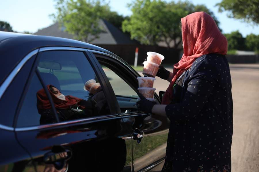 Noreen Choudhury begins a free meal delivery by asking the driver how many members there are in the family. She then gathers as many portions as needed and delivers them through the window while wearing a mask. (Liesbeth Powers/Community Impact Newspaper)