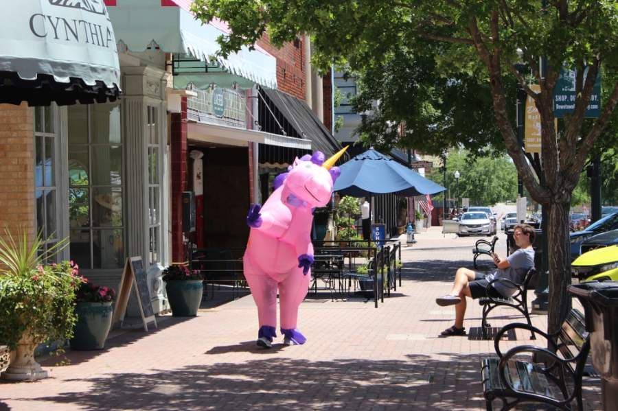 They do exist! A pink unicorn is spotted waving to people to downtown McKinney. (Miranda Jaimes/Community Impact Newspaper)