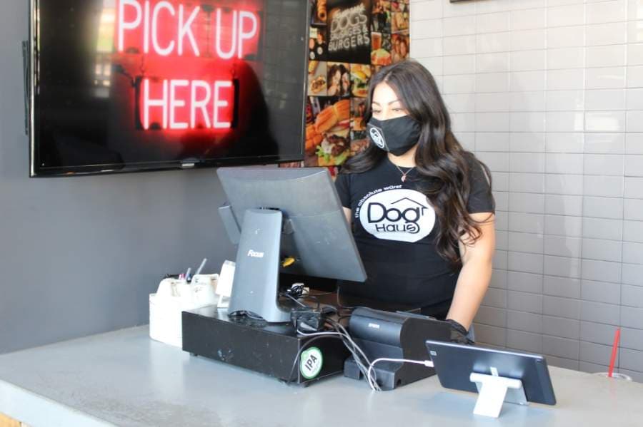 A masked employee takes an order at Dog Haus Biergarten, one of the only Richardson Restaurant Park businesses open to dine-in patrons. (Olivia Lueckemeyer/Community Impact Newspaper) 