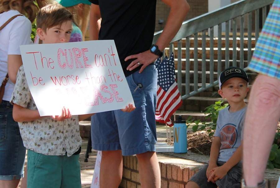 A child held up a sign that read, "The cure can't be worse than the disease." (Andy Li/Community Impact Newspaper)
