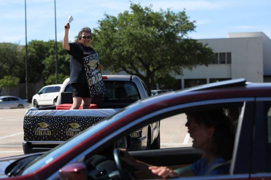 Farther down the line of teachers, Sara Weatherford, math teacher at Plano East Senior High School, stands in her truck bed, cheering on seniors and making noise with her cowbell. (Liesbeth Powers/Community Impact Newspaper)