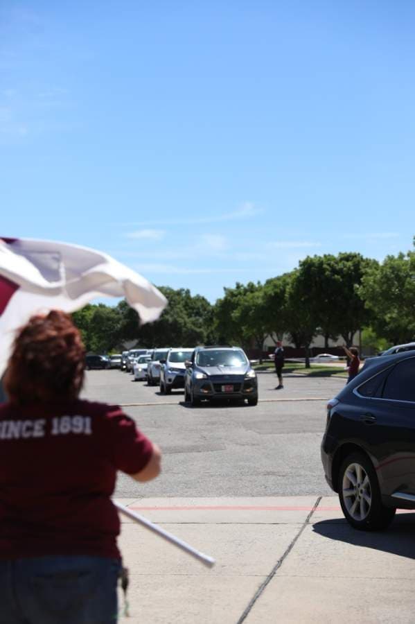 A line of cars with seniors and their families wrapped through the parking lots of Plano Senior High School and Plano East Senior High School, leading out onto the street. (Liesbeth Powers/Community Impact Newspaper)
