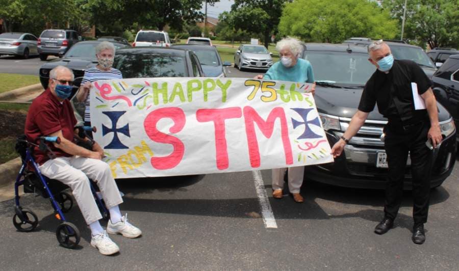 Members of Carl and Denise Starnes’ church, St. Thomas More Catholic Church, show their banner. From left are: Alex and Anne Rodriguez, Irene Berkel and Father Michael O’Connor. (Brian Perdue/Community Impact Newspaper)