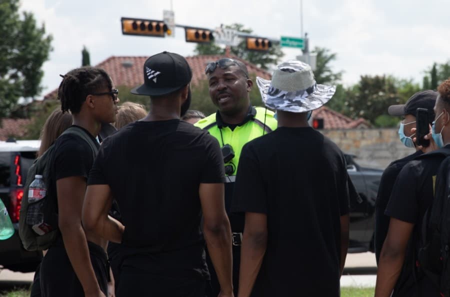 Plano Police officer Omar Landrum speaks to a small group of protesters, encouraging their decision to march peacefully. (Liesbeth Powers/Community Impact Newspaper)