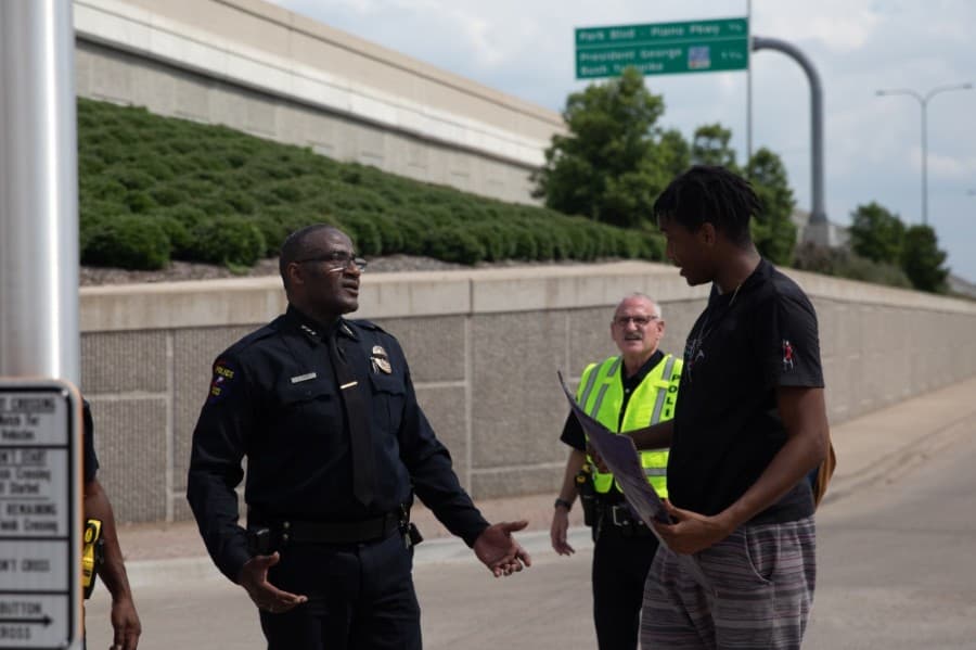 A protester who was led out of the turnaround lane at the intersection of Dallas Parkway and Parker Road speaks with Police Chief Ed Drain. (Liesbeth Powers/Community Impact Newspaper)