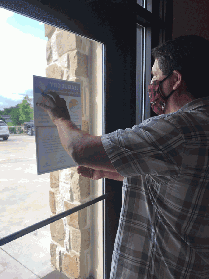 A business owner displays a sign indicating he took League City's pledge. (Courtesy city of League City)