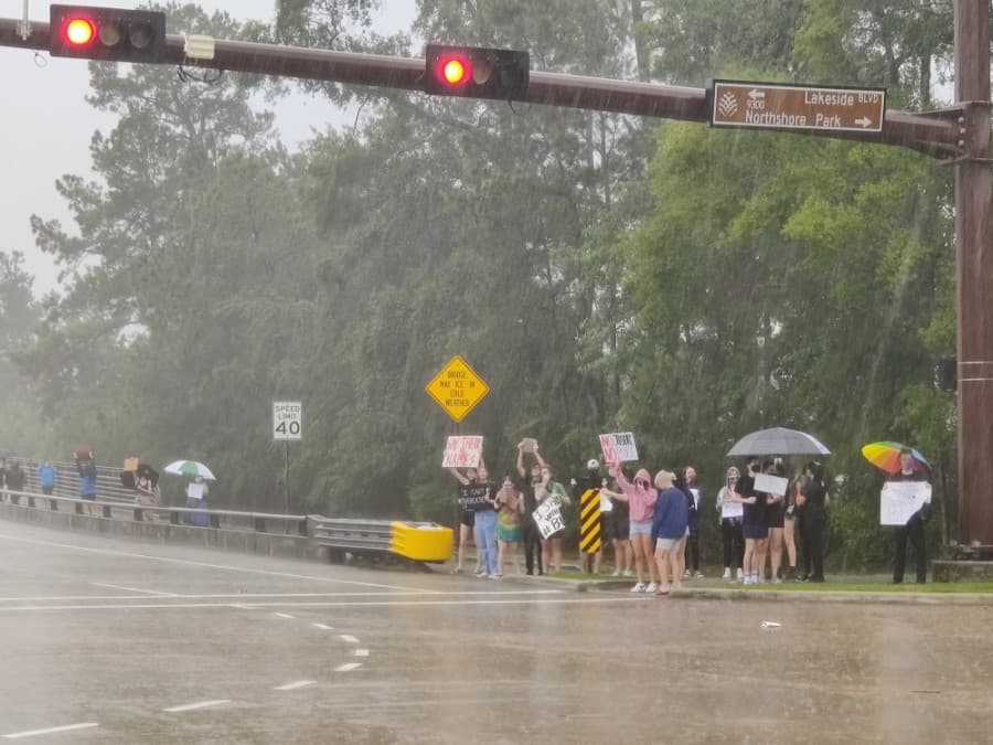 The June 3 march along Lake Woodlands Drive began in pouring rain, with demonstrators standing across the Lakeside Boulevard intersection and chanting at passing cars. (Ben Thompson/Community Impact Newspaper)