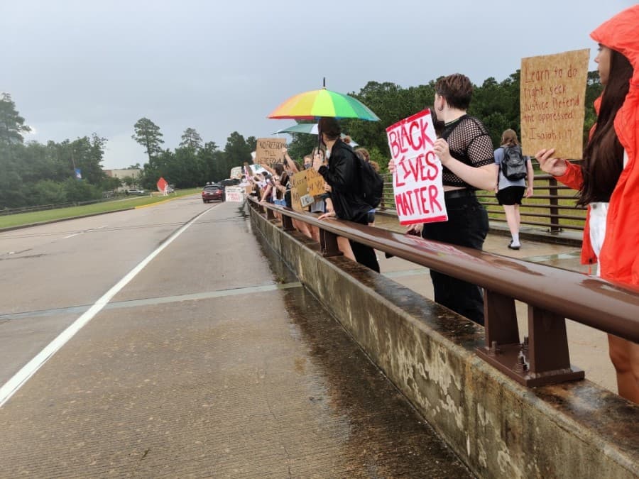 Some demonstrators stood along the Lake Woodlands Drive bridge to engage with passing vehicles and cheered when drivers honked or shouted responses while passing by. (Ben Thompson/Community Impact Newspaper)