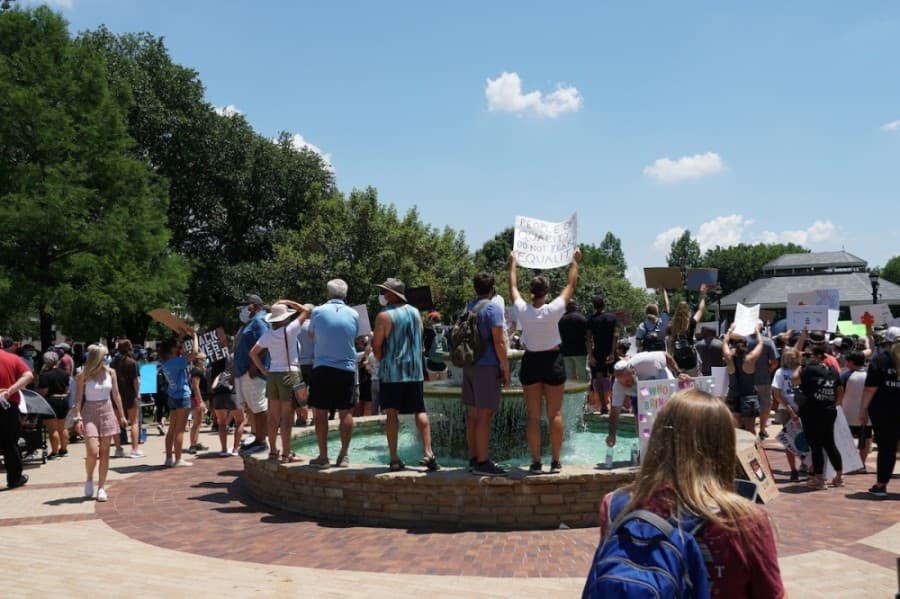 Protestors stand at the fountain in Southlake Town Square. (Gavin Pugh/Community Impact Newspaper)