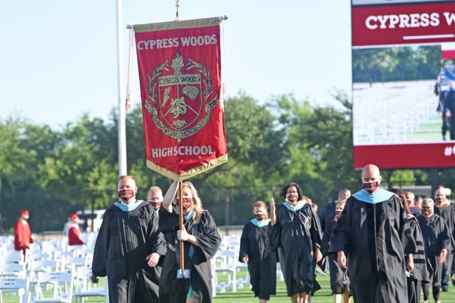 Cypress Woods High School students hold up a banner with a Cy Woods flag attached at a June 5 ceremony. (Courtesy Cy-Fair ISD)