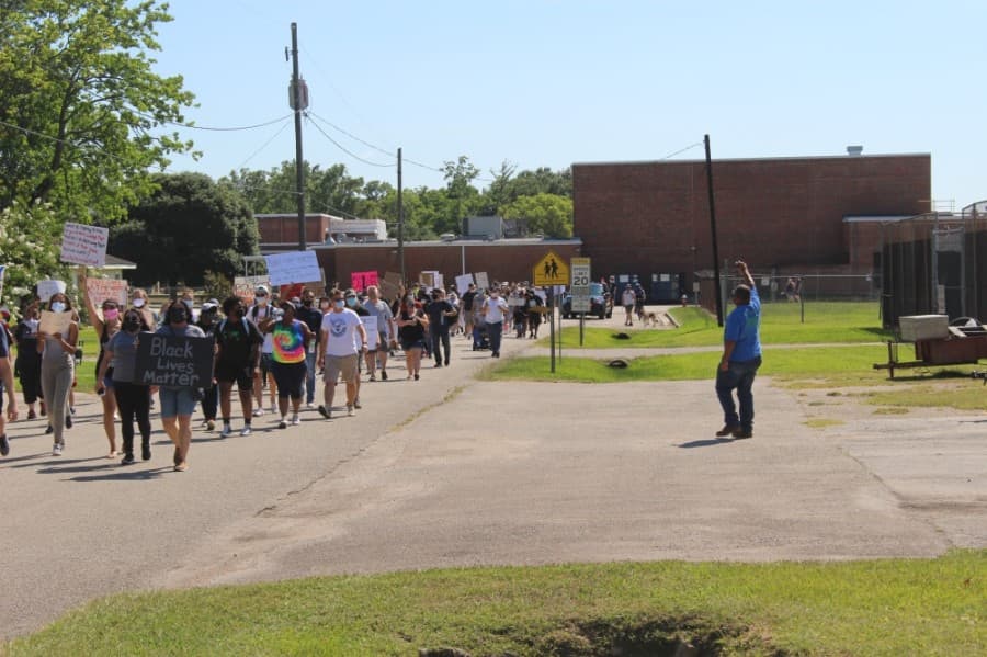 Protesters travel down School and Malone streets on their way to City Hall on June 13 with members of the community standing in the grass in support. (Dylan Sherman/Community Impact Newspaper)
