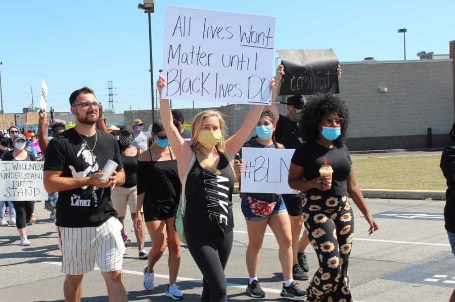 Jessica Seggebruch, one of the event organizers and a Tomball High School alum, holds a sign as she begins the 1-mile march to City Hall on June 13. (Anna Lotz/Community Impact Newspaper)
