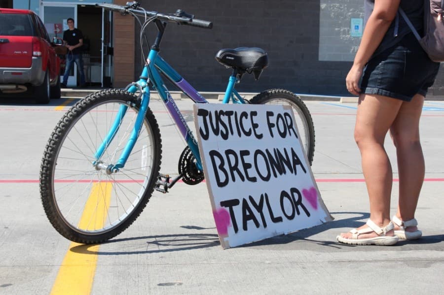 A sign calling for justice for Breonna Taylor, who was the black woman shot and killed in her own home by Louisville, Kentucky, police in March, rests in the H-E-B parking lot before the march starts. (Anna Lotz/Community Impact Newspaper)
