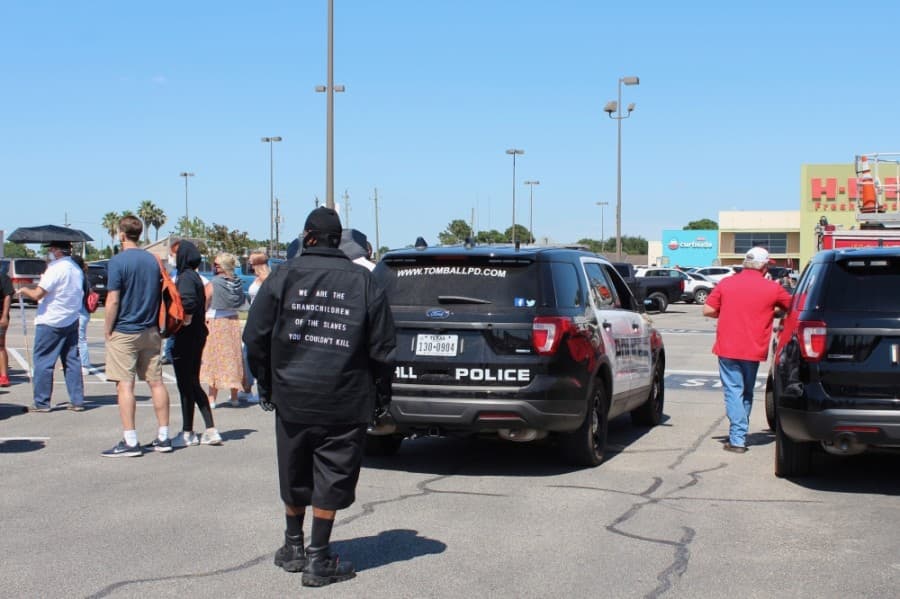The group gathered in the H-E-B parking lot to start the march, escorted by Tomball city officials. (Anna Lotz/Community Impact Newspaper)