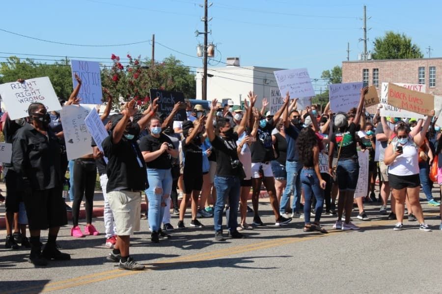 Protesters chant "Hands up, don't shoot!" upon gathering at Tomball City Hall on June 13. (Anna Lotz/Community Impact Newspaper)