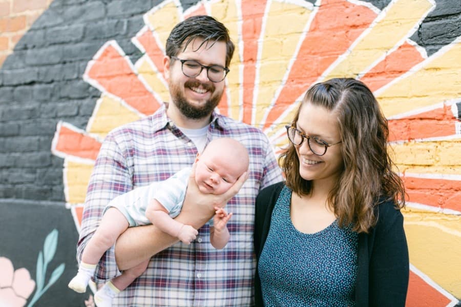 Andrew and Kate Jones take a photo with their new baby in front of their new mural on Fair & Square Imports. (Courtesy Cassie Loree Photography)