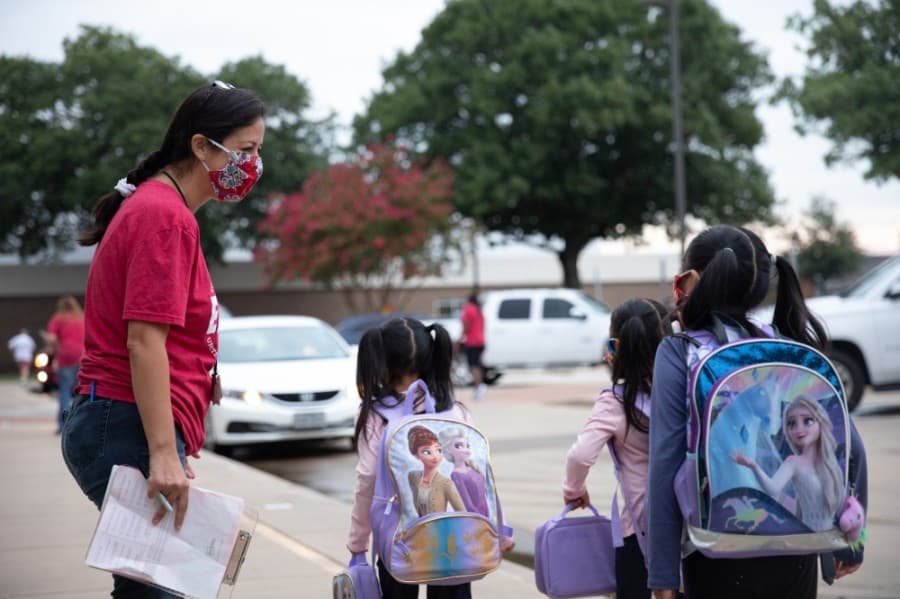 A staff member greets students as they approach Weatherford Elementary School. (Liesbeth Powers/Community Impact Newspaper)