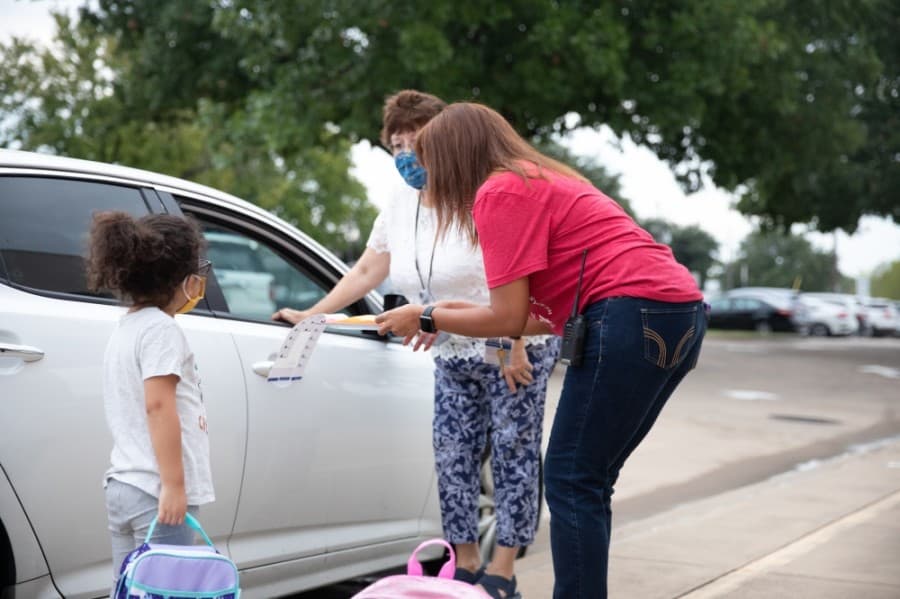 A staff member assigns a student indicating whether the student will be picked up or ride the bus home at the end of the day. (Liesbeth Powers/Community Impact Newspaper)