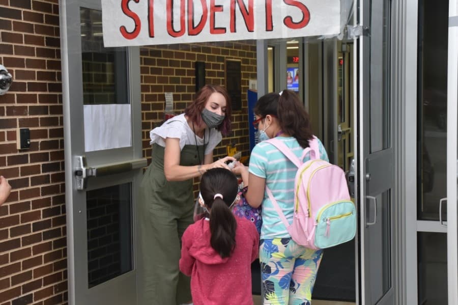 A staff member at Weatherford Elementary School gives students hand sanitizer before they walked into the building. (Makenzie Plusnick/Community Impact Newspaper)