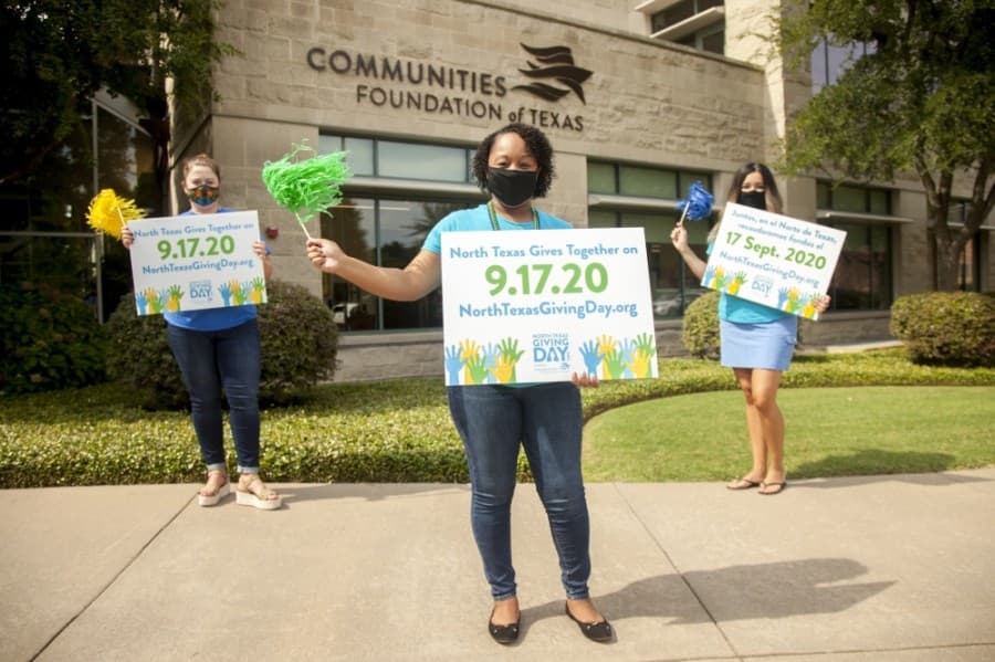 Communities Foundation of Texas' Lisa Causey, Morgan Spann and Erica Lopez hold up North Texas Giving Day yard signs. (Courtesy Kim Leeson/Communities Foundation of Texas)