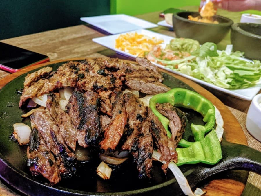 Beef fajitas ($21.75): Beef skirt steak is charbroiled over a bed of grilled veggies and served with rice, beans, guacamole, sour cream, pico, shredded cheese, lettuce and choice of tortillas. (Courtesy Tex-Mex Grill and Bar)