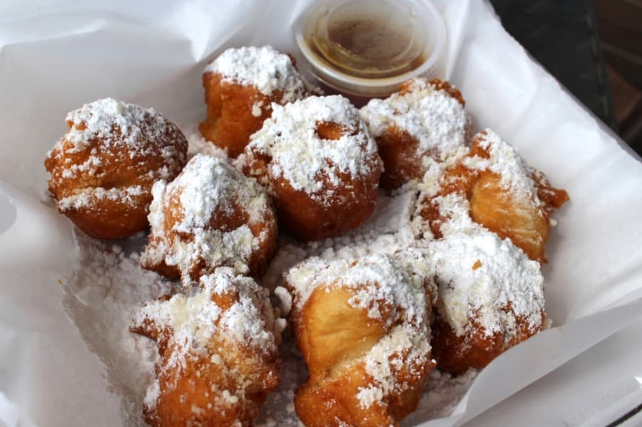 Beignets are a French donut dusted with powdered sugar and served with a caramel sauce. (Olivia Lueckemeyer/Community Impact Newspaper)