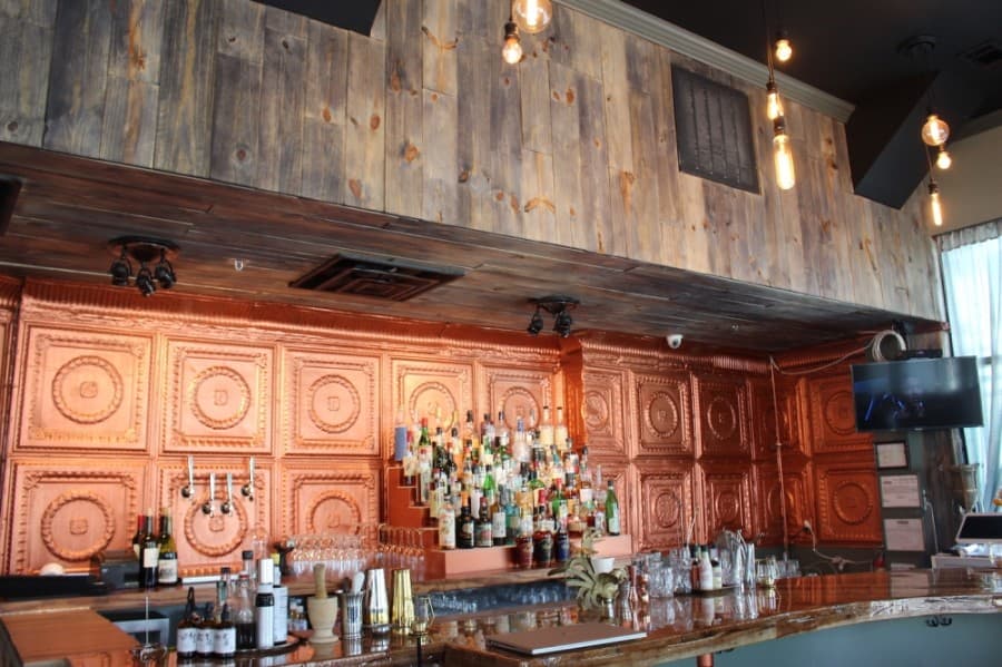 A copper backdrop greets guests as they approach the bar area at CT Provisions in McKinney. (Miranda Jaimes/Community Impact Newspaper)