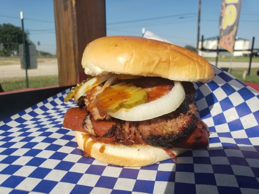 CJ's Big Boy sandwich ($10) comes with brisket, sausage, onions and pickles. (Ali Linan/Community Impact Newspaper)