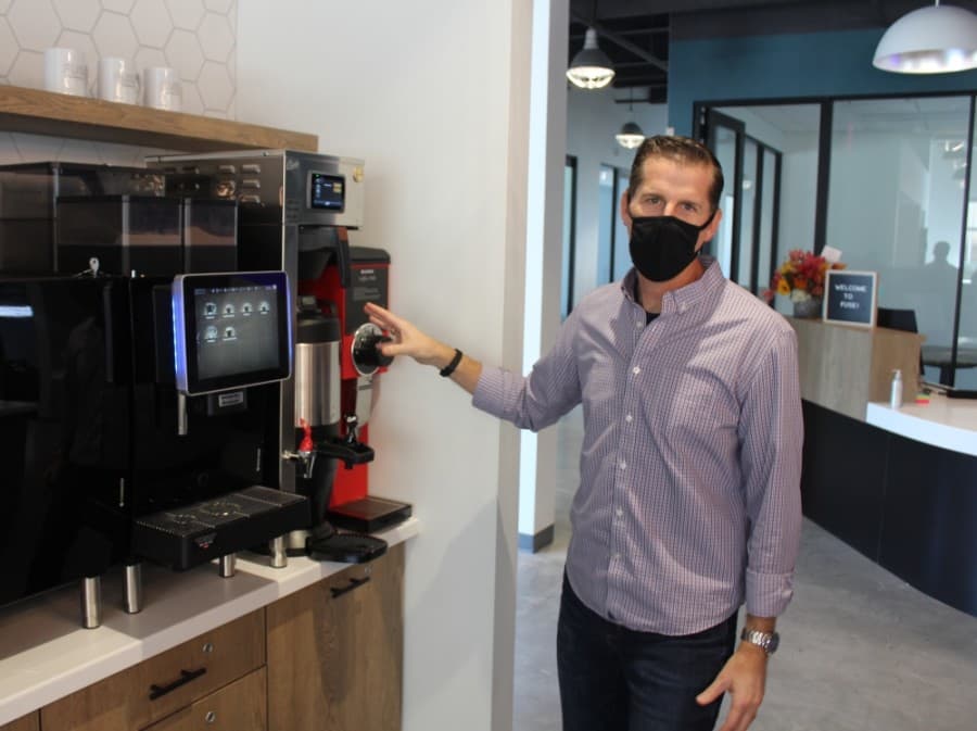 FUSE Director of Operations John Herring stands beside a $28,000 gourmet coffee bot at the new Bee Cave facility. (Brian Perdue/Community Impact Newspaper)