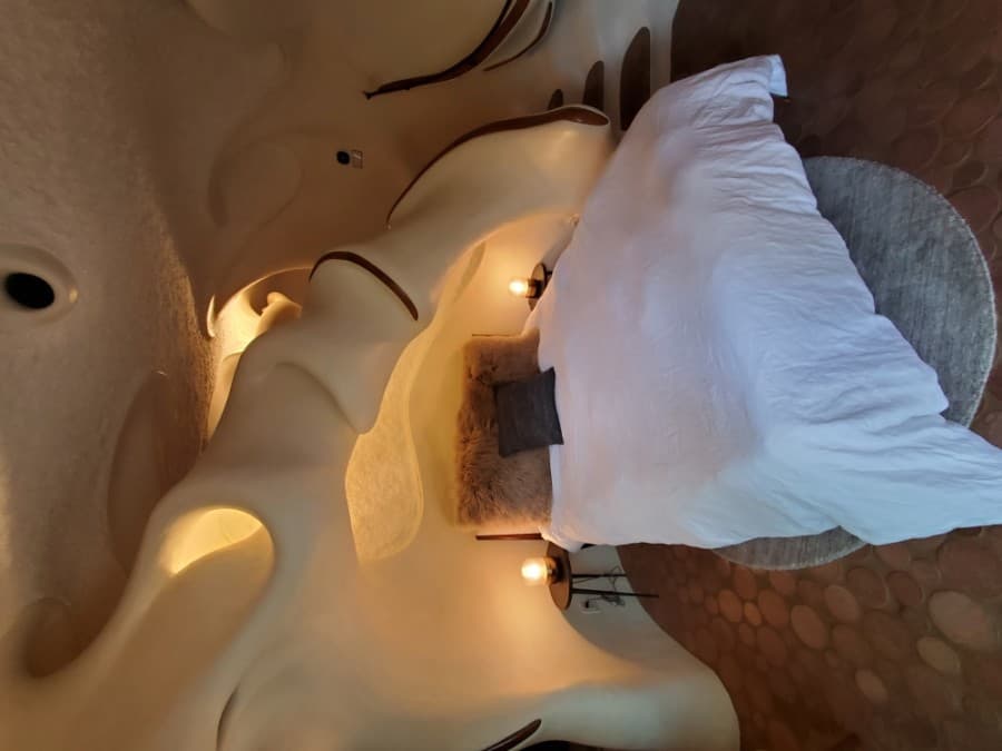 The bedroom has a curvy ceiling.