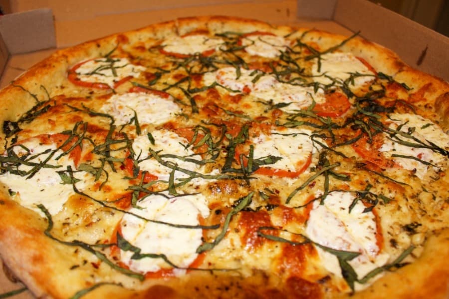 Margherita pie ($20-$30) is a pizza topped with garlic sauce, tomato slices, mozzerella and basil. (Kelly Schafler/Community Impact Newspaper)