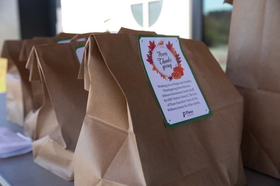 Roughly 100 members drove along a cone-lined path of city staff and council members bearing signs and smiles before opening their trunks for a staff-made, packaged meal at a Nov. 18 Thanksgiving event. (Liesbeth Powers/Community Impact Newspaper)