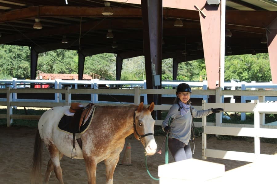 A boarding client at Callegari Equestrian Center brings her horse in from one of the centers covered arenas. (Shawn Arrajj/Community Impact Newspaper)