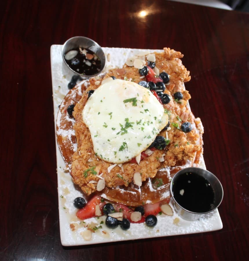 Chicken and waffles ($14.50): Cajun fried chicken breast brined in Cajun spices and cane syrup served over a Belgian waffle with shaved almonds, fresh berries and local honey.