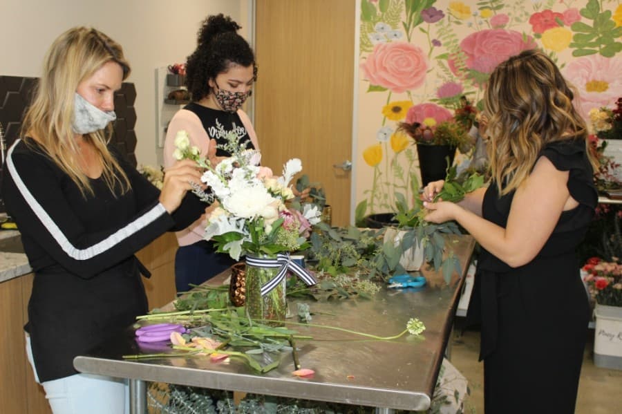 Piney Rose Floral owner Taylor Handfelt helps employees work on fresh arrangements. (Andrew Christman/Community Impact Newspaper)