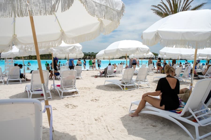 people sitting on chairs on a sandy beach