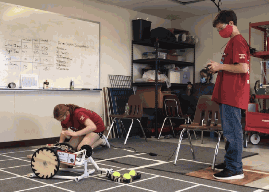 Robotics team member Sadie Gafka, the spotter, checks the “cells” using a tester to see if they are infected, uninfected or immune, while member Arturo Sanchez picks up the “vaccines” to deliver to the frames or platforms to immunize cells. (Courtesy Jayme Sanchez)