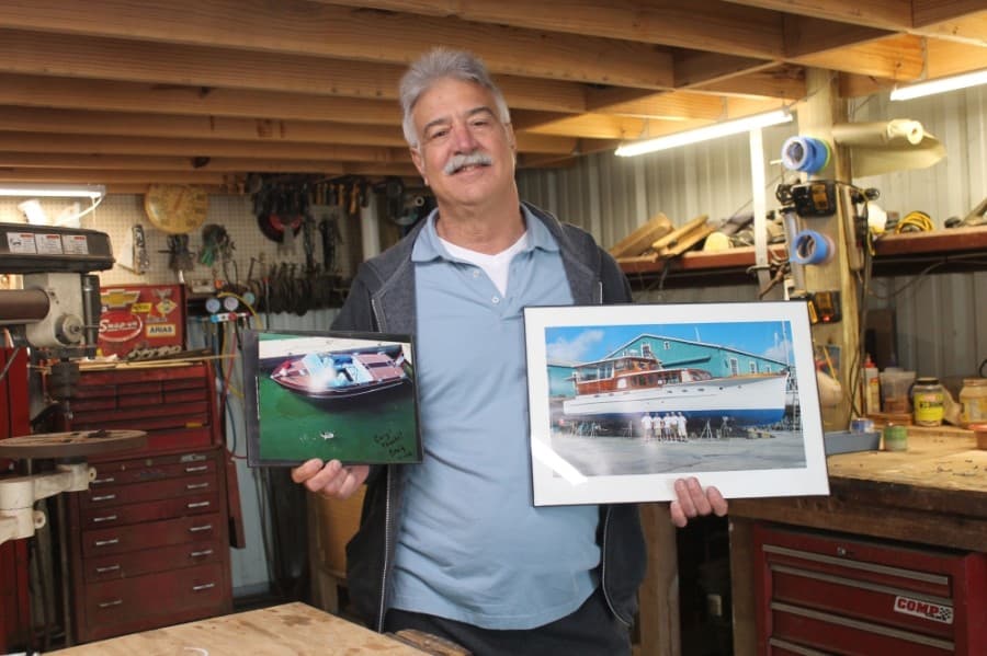 Hoyle poses with photos of him and previously completed boat projects in his Kemah shop.