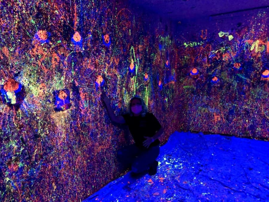 Amber Gordon poses in the splatter room, which also glows in the dark. (Sally Grace Holtgrieve/Community Impact Newspaper)