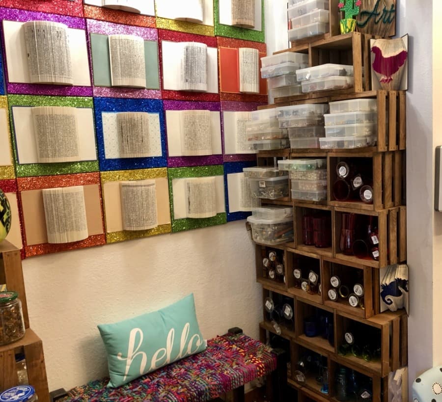 Bottles for smash glass projects are housed next to book folding art. (Sally Grace Holtgrieve/Community Impact Newspaper)