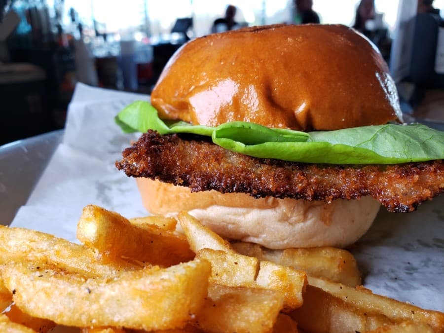A Schnitzel sandwich featuring lettuce, tomato, onion, ‘shed-made pickles, and Dijon mustard. Price is $13.50. (Courtesy Watershed)