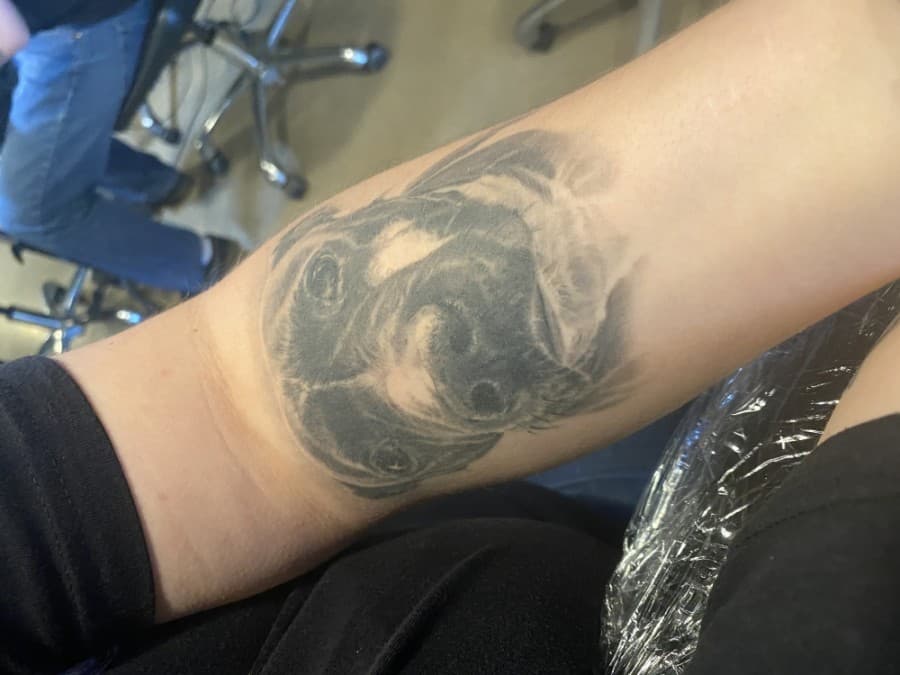 A client shows off a recent tattoo of their dog they received at Faces in the Dark.