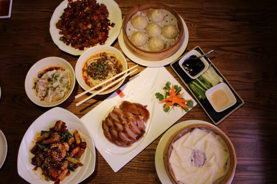 From top left clockwise: Crispy spicy chicken ($12.95), Pork soup dumplings ($8.95), Peking duck with duck sauce, housemade pancakes, shredded onions and cucumbers and brown sugar ($25.59), Grilled pork ribs and shrimp ($15.95), Hot oil wontons ($6.95) and Dan Dan Noodle soup ($6.95) (Shawn Arrajj/Community Impact Newspaper)