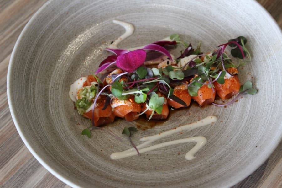 The truffle salmon roll ($16) features salmon served with truffle aioli, microgreens and kizimi wasabi. (Adriana Rezal/Community Impact Newspaper)